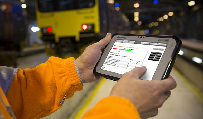 A construction worker holding and viewing information on a rugged tablet.