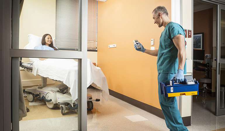 A doctor viewing a patient's information on his mobile device as he's walking in to see her.